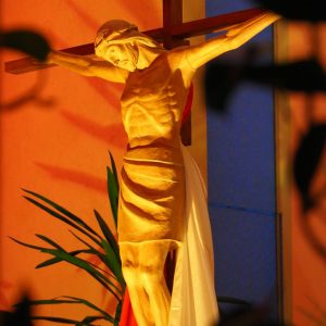 Illuminated statue of Jesus Christ on the cross inside a church showcasing divine sacrifice.