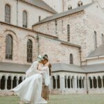 A couple embraces in front of the historic Nivelles Cathedral in Belgium, symbolizing love and tradition.