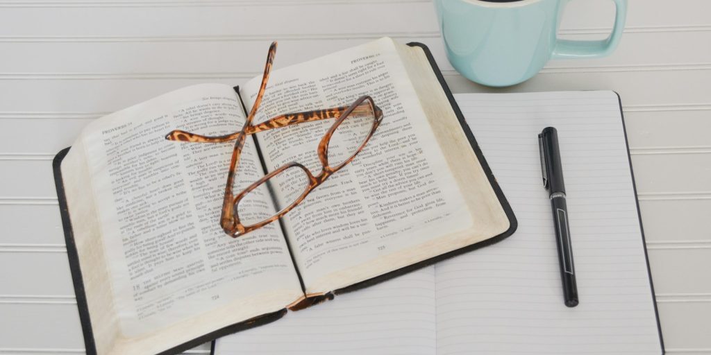 flat lay photography of tortoiseshell eyeglasses on top of book near black pen and teal mug