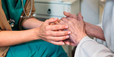 Female doctor giving encouragement to elderly patient by holding her hands