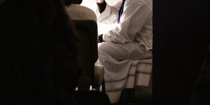 man wearing white bathrobe sitting on bed
